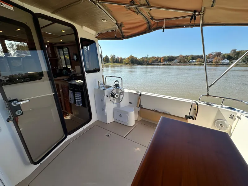 Slide: The Image of 2014 Ranger Tugs R-31CB boat interior with river view, featuring helm and seating area. - 11