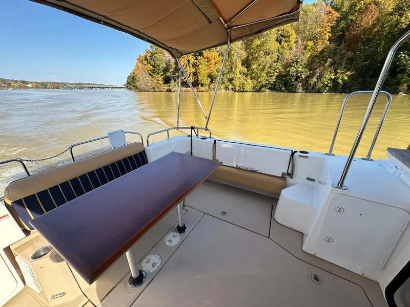 Slide: The Image of 2014 Ranger Tugs R-31CB boat with outdoor seating and table on a calm river. - 12