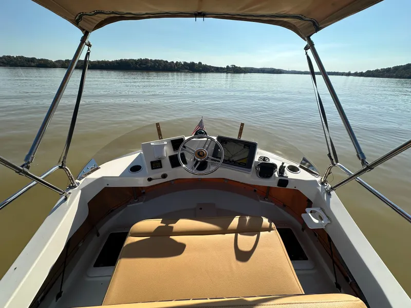 Slide: The Image of 2014 Ranger Tugs R-31CB helm view, featuring navigation equipment and tan seating on calm waters. - 14