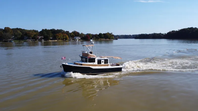 Slide: The Image of 2014 Ranger Tugs R-31CB cruising on a calm lake under a clear blue sky. - 3