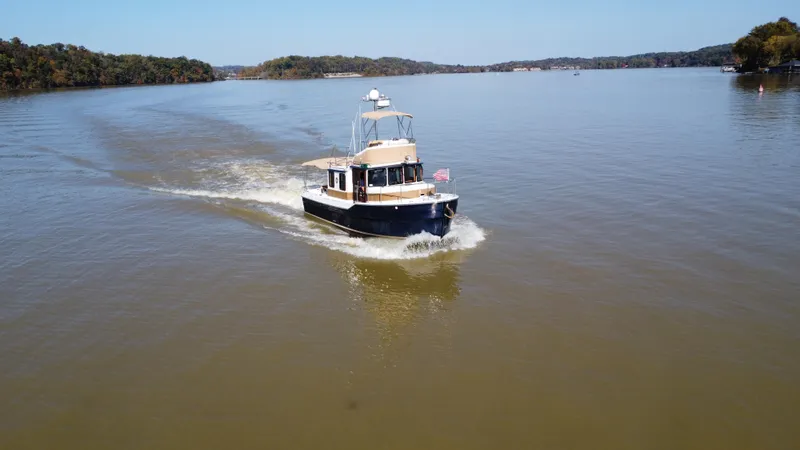 Slide: The Image of 2014 Ranger Tugs R-31CB cruising on a calm lake with scenic background. - 5