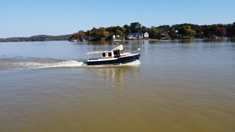 Slide: The Image of 2014 Ranger Tugs R-31CB cruising on a calm lake with scenic shoreline. - 6