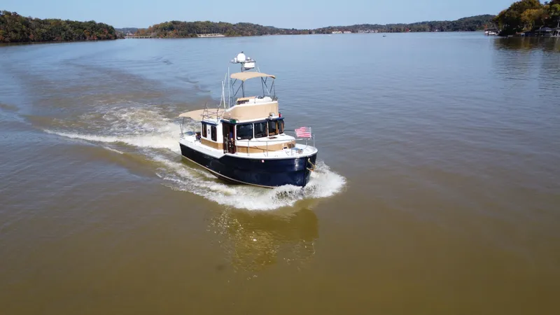 Slide: The Image of 2014 Ranger Tugs R-31CB cruising on a calm lake with scenic background. - 7
