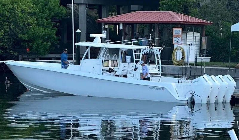 Slide: The Image of 2023 Contender 44 ST boat docked, featuring multiple outboard engines and sleek design. - 0