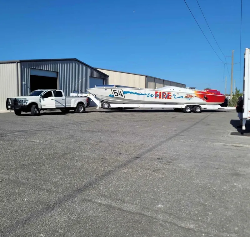 Slide: The Image of Truck towing 1994 Apache 47 Fire Water boat near warehouse. - 3