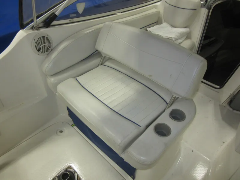Slide: The Image of 2004 Bayliner 245 boat interior with white seating and cup holders. - 10