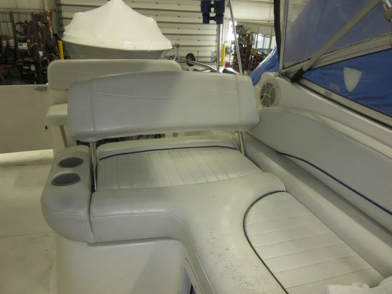 Slide: The Image of 2004 Bayliner 245 boat interior with white seating and cup holders. - 11