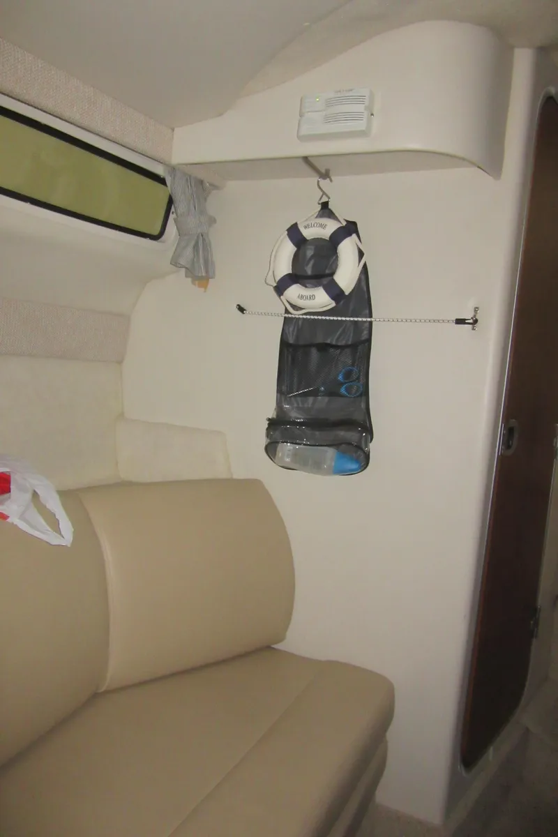 Slide: The Image of Interior of 2004 Bayliner 245 boat with beige seating and life jacket hanging. - 15