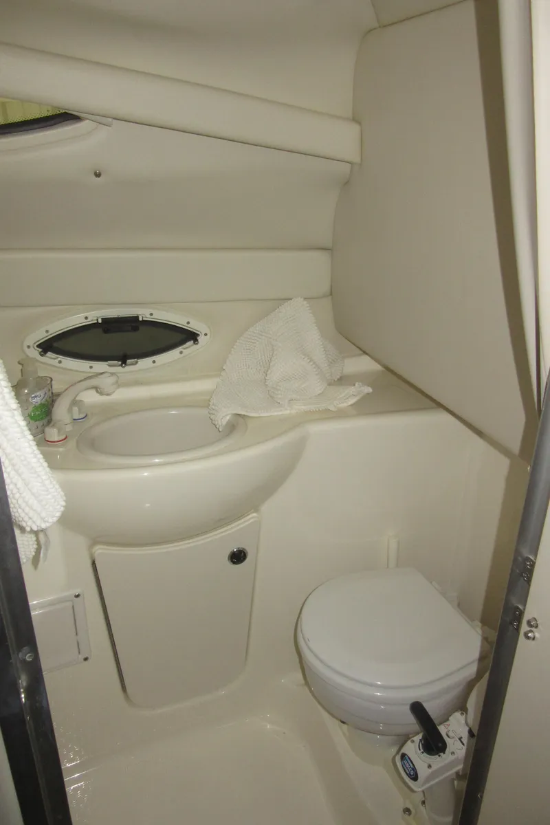 Slide: The Image of 2004 Bayliner 245 boat bathroom with sink, toilet, and porthole window. - 16