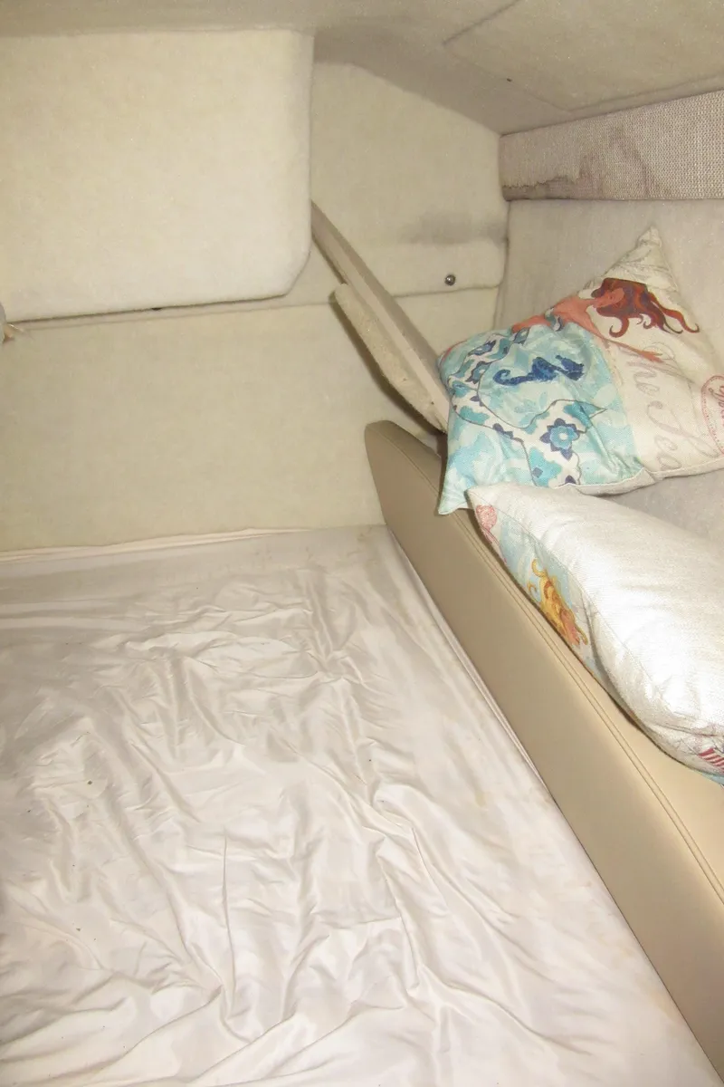 Slide: The Image of 2004 Bayliner 245 cabin interior with bedding and decorative pillows. - 17