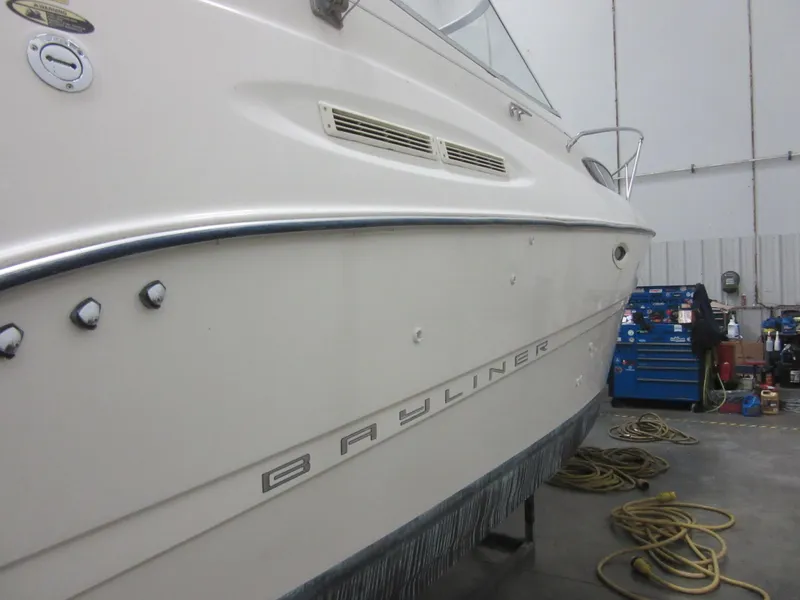 Slide: The Image of 2004 Bayliner 245 boat in a workshop, side view with tools and equipment nearby. - 22