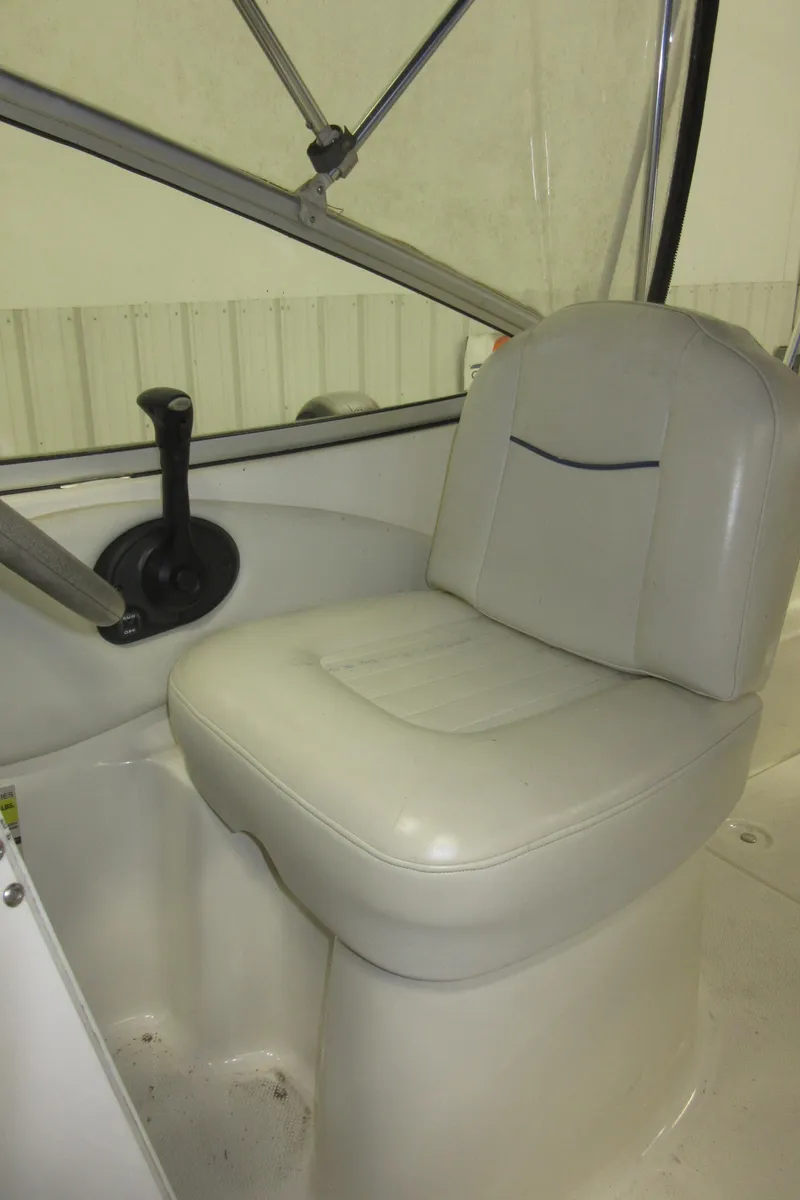 Slide: The Image of 2004 Bayliner 245 boat interior with white captain's seat and steering wheel. - 24