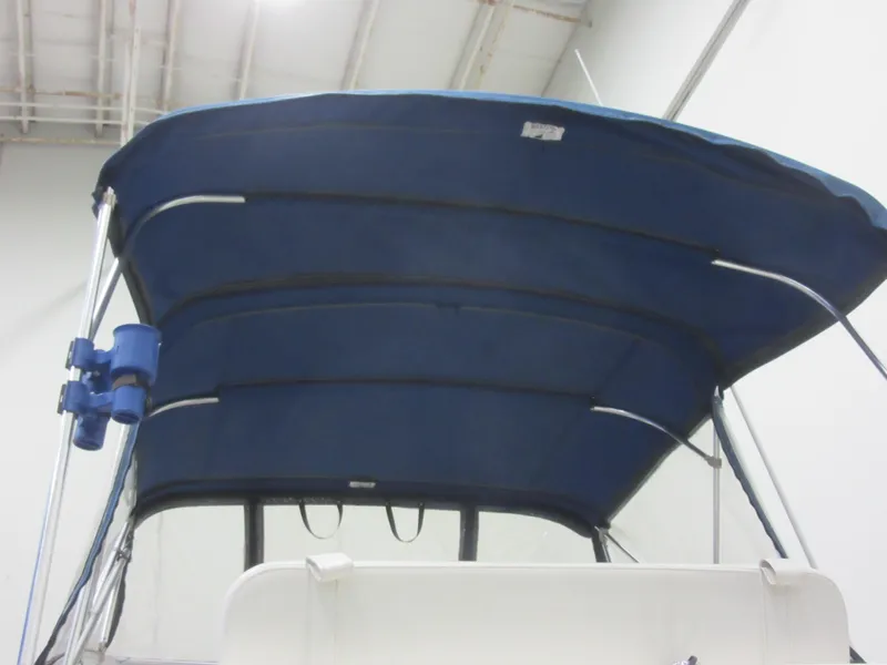 Slide: The Image of 2004 Bayliner 245 boat with blue bimini top in indoor storage. - 6