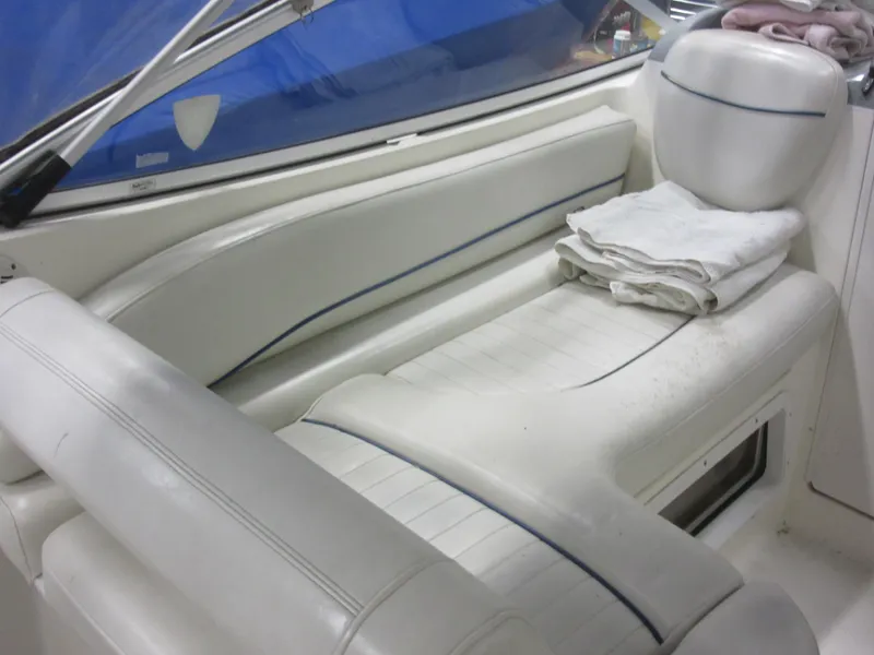 Slide: The Image of 2004 Bayliner 245 boat interior with white seating and folded towels. - 8