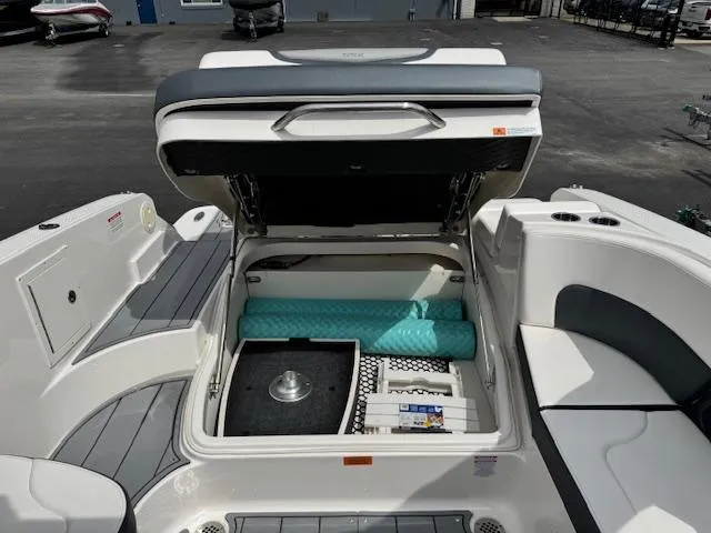 Slide: The Image of 2021 Chaparral 267 SSX OB boat storage compartment open, revealing interior items and seating area. - 17
