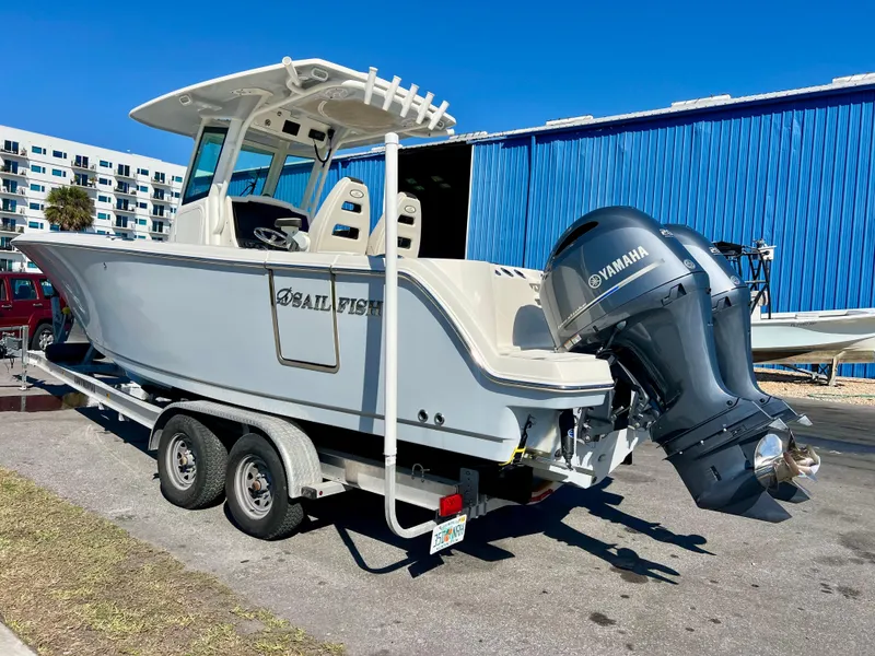 Slide: The Image of 2023 Sailfish 272 CC boat on trailer with Yamaha engine, parked near blue building. - 3