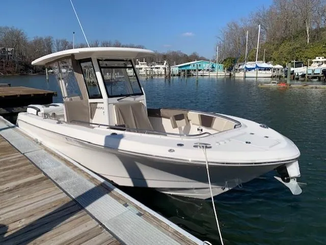 Slide: The Image of 2019 Robalo R272 Center Console boat docked by a serene waterfront. - 0