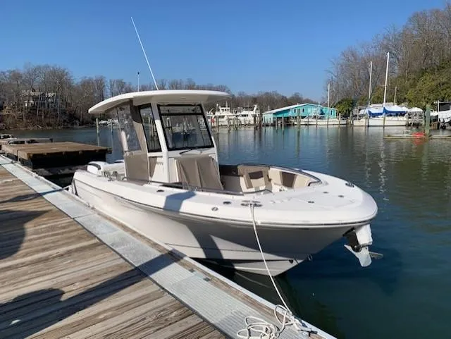 Slide: The Image of 2019 Robalo R272 Center Console boat docked on a calm lake under clear blue skies. - 2