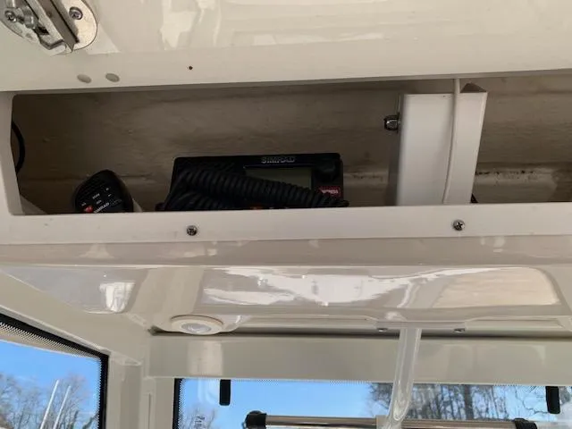 Slide: The Image of 2019 Robalo R272 Center Console storage compartment with marine radio equipment. - 24