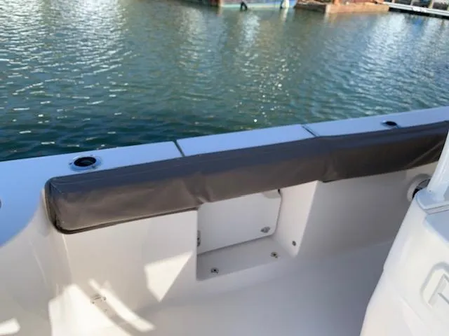 Slide: The Image of 2019 Robalo R272 Center Console boat interior with cushioned seating by the water. - 6