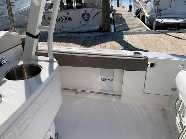 Slide: The Image of 2019 Robalo R272 Center Console boat interior at dock, featuring seating and stainless steel fixtures. - 7