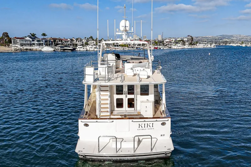 Slide: The Image of 2018 Fleming 58 Pilothouse yacht on calm water, with coastal cityscape in background. - 16