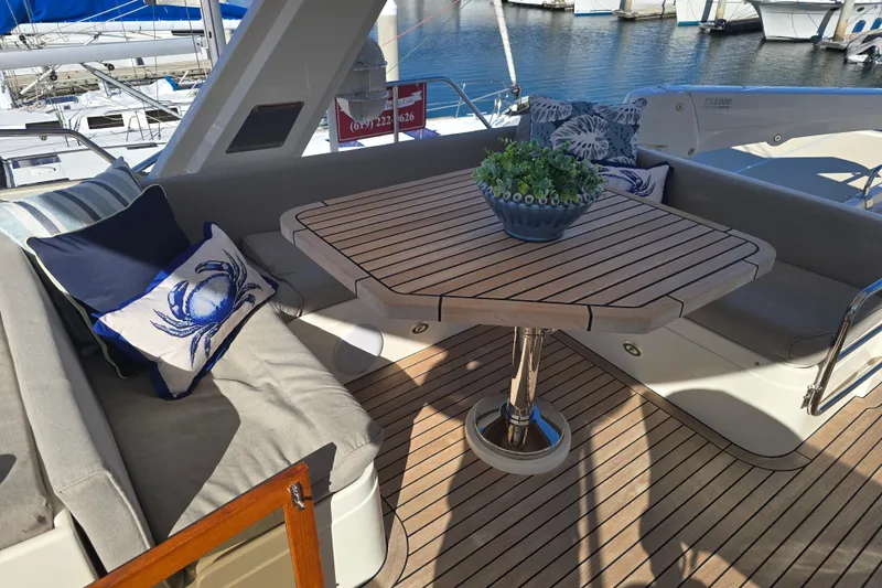 Slide: The Image of Luxurious 2018 Fleming 58 Pilothouse yacht deck with cushioned seating and wooden table. - 26