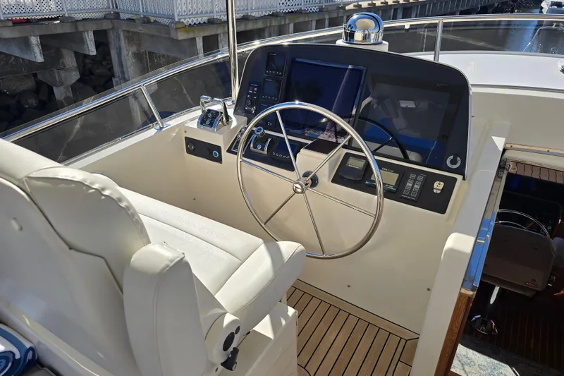 Slide: The Image of 2018 Fleming 58 Pilothouse helm with steering wheel, navigation controls, and comfortable seating. - 29