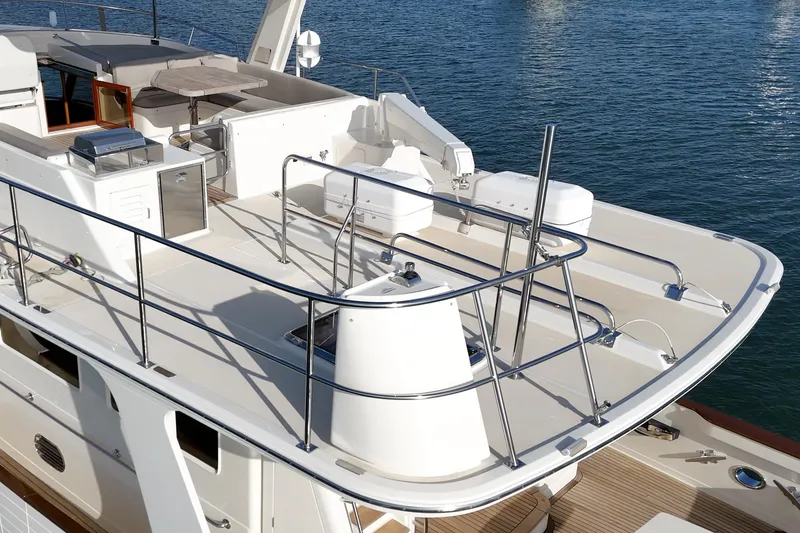 Slide: The Image of 2018 Fleming 58 Pilothouse yacht deck with railing and seating, docked on calm water. - 31