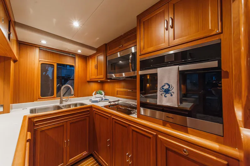 Slide: The Image of Luxurious kitchen interior of 2018 Fleming 58 Pilothouse yacht with wood cabinetry and modern appliances. - 49