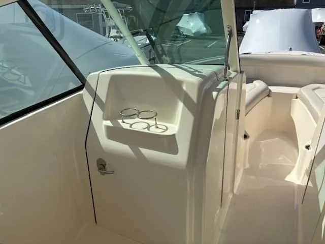 Slide: The Image of 2013 Pursuit 265 Dual Console boat interior with cup holders and seating area. - 13