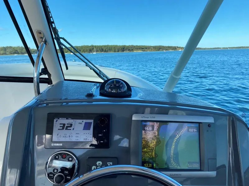 Slide: The Image of 2013 Pursuit D 265 Dual Console boat dashboard with navigation screens on a clear day. - 4