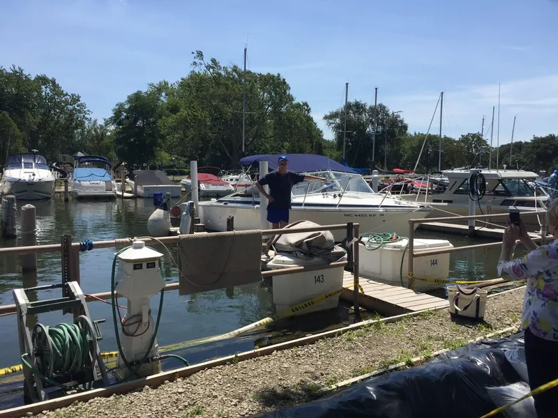 Slide: The Image of Man standing near a 1976 Bertram 26 Moppie boat at a marina dock. - 18