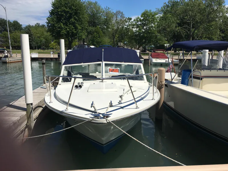 Slide: The Image of 1976 Bertram 26 Moppie boat docked at a marina, surrounded by trees. - 2