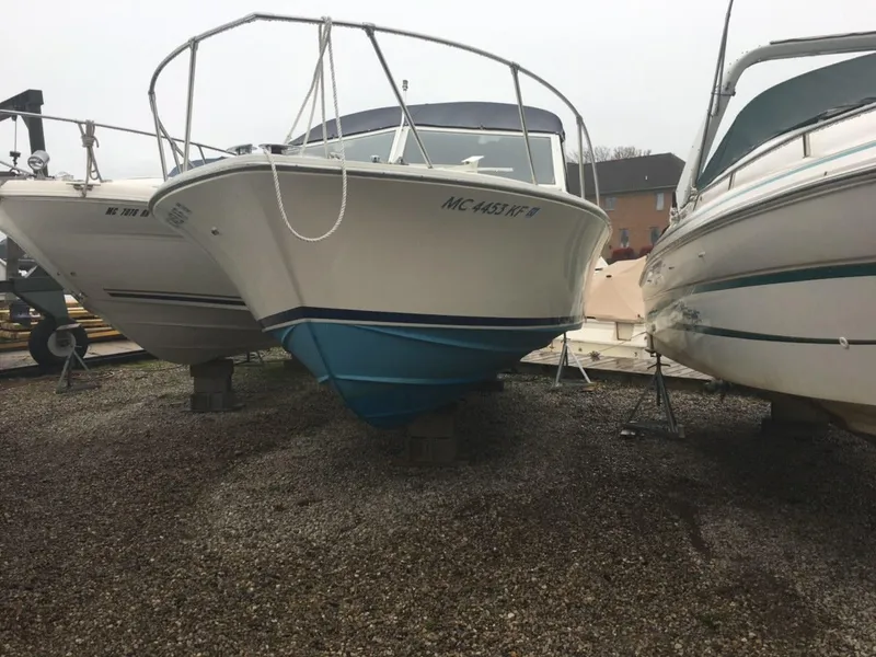 Slide: The Image of 1976 Bertram 26 Moppie boat on gravel, flanked by other boats. - 3