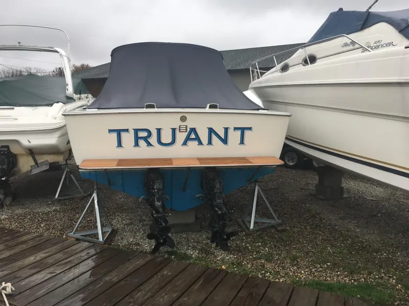Slide: The Image of 1976 Bertram 26 Moppie boat named "Truant" on display, covered and docked. - 4