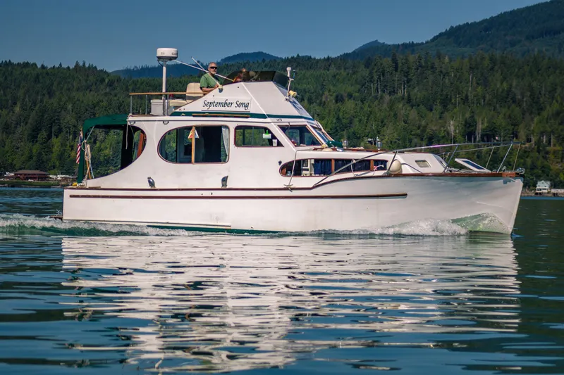 The Image of 1956 Monk 33 Sedan Cruiser on serene lake with forested hills in background. - 1