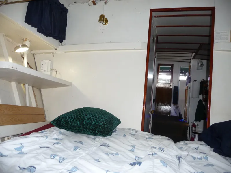 Slide: The Image of Interior of a 1956 Monk 33 Sedan Cruiser with cozy bedding and nautical decor. - 10