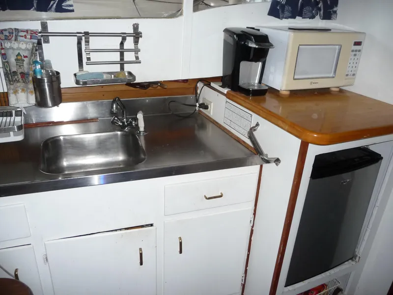 Slide: The Image of 1956 Monk 33 Sedan Cruiser kitchen with sink, microwave, coffee maker, and compact fridge. - 14