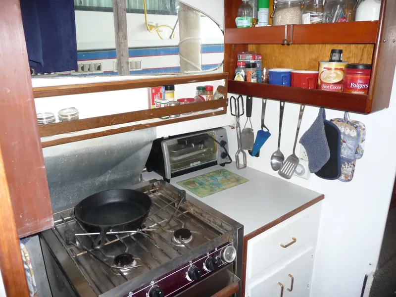 Slide: The Image of Compact kitchen in a 1956 Monk 33 Sedan Cruiser with stove, utensils, and storage shelves. - 15