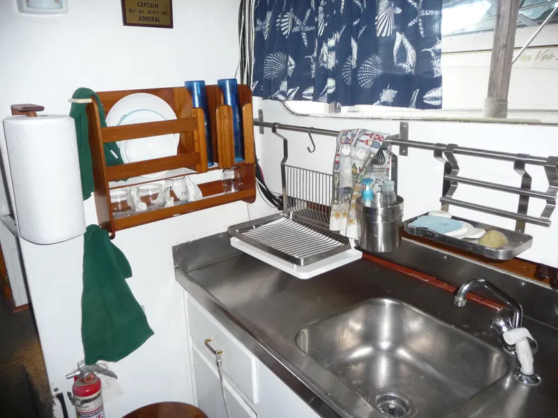 Slide: The Image of 1956 Monk 33 Sedan Cruiser kitchen with sink, dish rack, and nautical decor. - 16