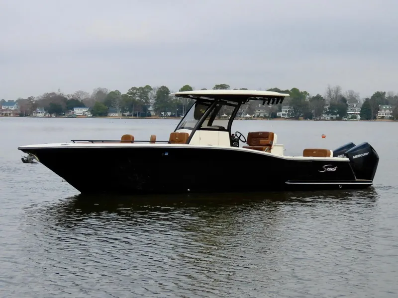 The Image of 2023 Scout 277 LXF boat on calm water, side view, with trees in the background. - 1