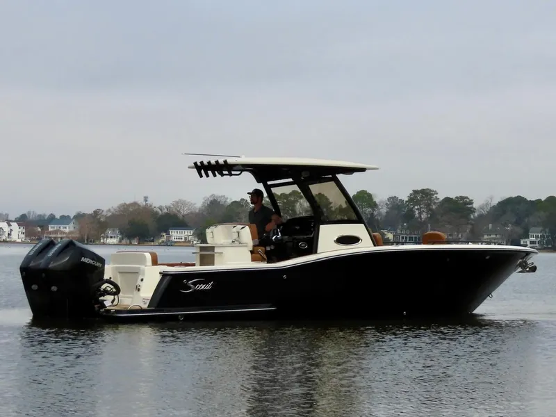 Slide: The Image of 2023 Scout 277 LXF boat on calm water, side view, with trees in the background. - 6