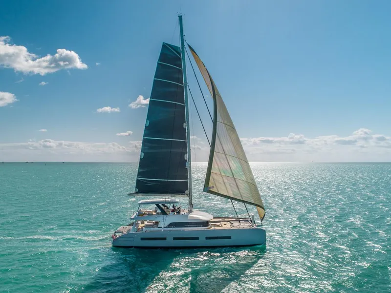 Slide: The Image of 2020 Lagoon SEVENTY 7 catamaran sailing on clear blue ocean under sunny skies. - 0