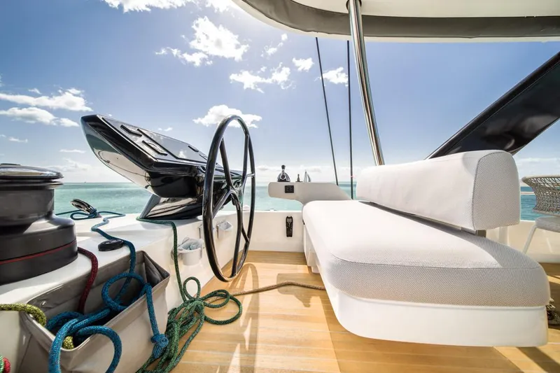 Slide: The Image of Luxurious 2020 Lagoon SEVENTY 7 yacht deck with steering wheel and seating, under sunny skies. - 49