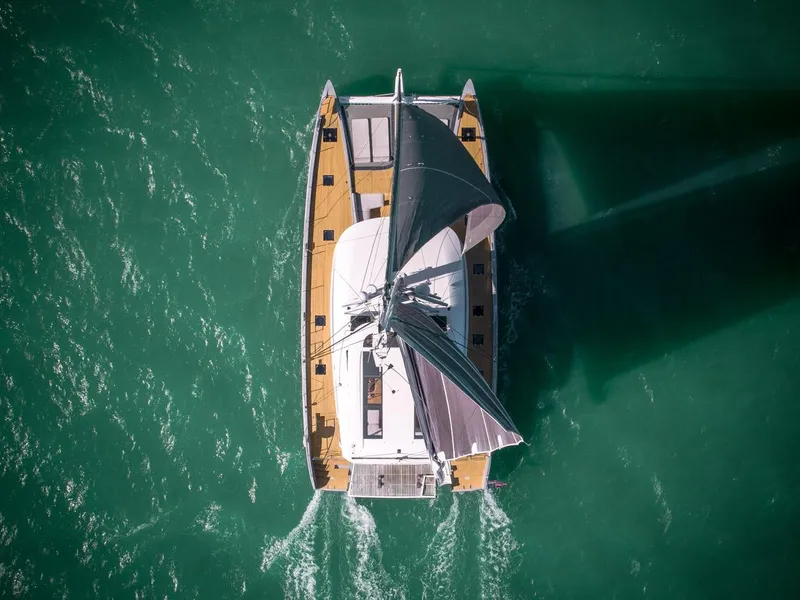 Slide: The Image of Aerial view of 2020 Lagoon SEVENTY 7 catamaran sailing on turquoise water. - 8
