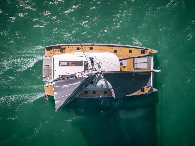 Slide: The Image of Aerial view of 2020 Lagoon SEVENTY 7 catamaran sailing on turquoise water. - 9