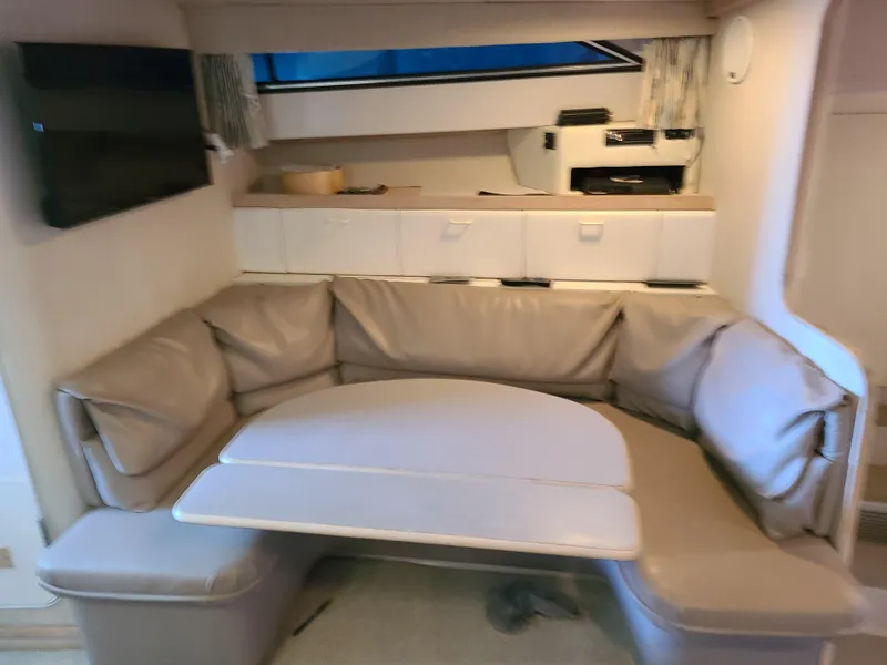 Slide: The Image of Interior of a 1992 Four Winns Express Cruiser with beige seating and a table. - 10