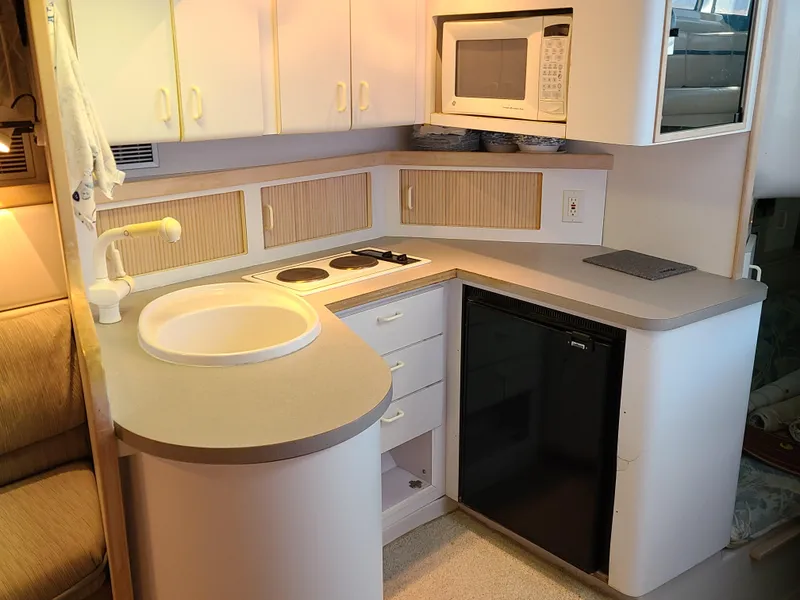 Slide: The Image of Compact kitchen in a 1992 Four Winns Express Cruiser with sink, stove, and microwave. - 12
