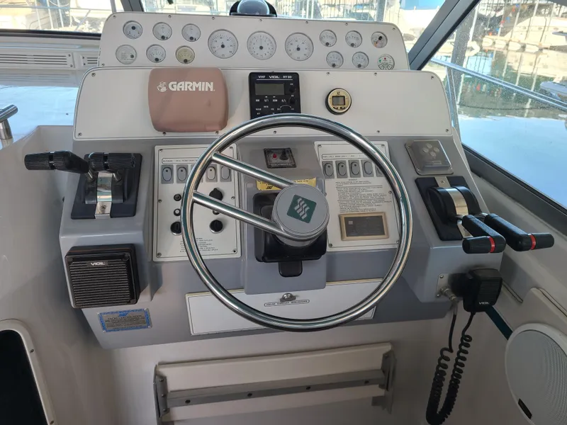Slide: The Image of 1992 Four Winns Express Cruiser helm with steering wheel and navigation instruments. - 8